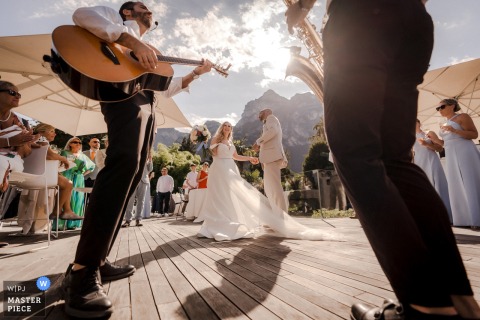 At Du Lac et Du Parc Grand Resort in Riva del Garda, Italy, musicians invite the newlyweds onto the dance floor for their first dance, captured from a dramatic wide, low angle.
