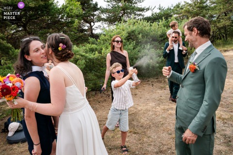 In Valence, France, a young boy playfully sprays the groom with a water bottle outside, adding a lighthearted and fun moment to the wedding celebration.