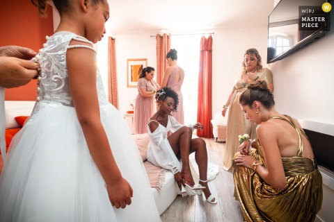 At Domaine de Belisle in Charente, the bride finishes getting ready, surrounded by her bridesmaids and daughter in a warm and supportive atmosphere before the ceremony.