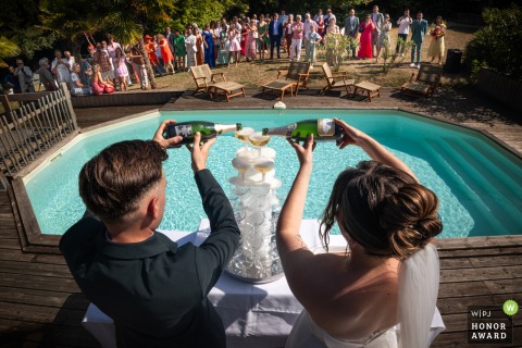 Domaine de Belisle in Charente features the couple serving a flowing champagne fountain by the pool, inviting guests to celebrate with a sparkling toast.