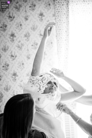 In Corvallis, Montana, the bride gets into her wedding dress in a softly lit room, the black-and-white photo giving the moment a timeless, vintage feel.