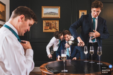 At Château Larteau in Gironde, France, the groomsmen share a moment of camaraderie and laughter with the groom during the wedding preparations.