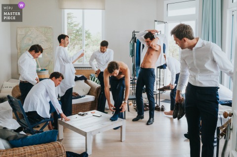 At the preparation venue in Arcachon, the groom and his groomsmen get dressed together before the wedding ceremony, sharing an intimate and anticipatory moment.