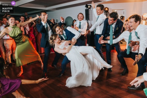 At Tir au Vol Hall in Arcachon, the newlyweds dance together on the dance floor, surrounded by guests celebrating and enjoying the lively wedding reception.
