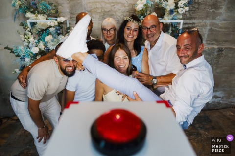 In front of the photobooth, a group poses for a fun photo as one man lifts his leg high, showing impressive flexibility and adding a playful touch to the moment.
