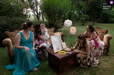 At Locanda nel Frutteto in Novi di Modena, Italy, the bride’s friends care for the couple’s young daughter, while one takes the opportunity to write a keepsake message.