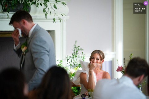 At Slindon College in Arundel, the groom wipes away tears with a handkerchief during his speech, while the bride covers her expression with her hand.
