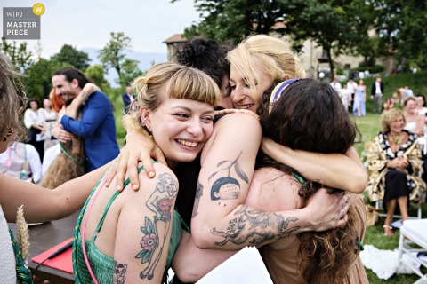At Ghisolfa Farmhouse in Lecco, Italy, the bride shares a joyful group hug with her bridesmaids after the ceremony, celebrating friendship and warm wedding moments.