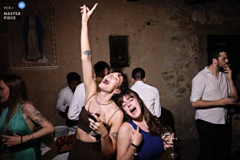 At Ghisolfa Farmhouse in Lecco, Italy, two girls dance and sing at the top of their lungs during a lively wedding celebration.