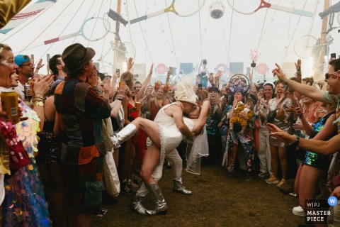 Under the vibrant lights of the dance tent at Wilderness, the newlyweds share their intimate first dance amidst the joyous energy of their unique festival wedding reception.