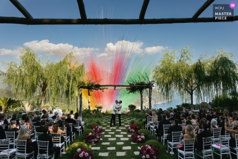 Against the stunning backdrop of the Amalfi Coast, a couple shares their first kiss at Villa Eva in Ravello as vibrant, colorful smoke cannons erupt into the sky.