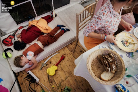 In Kerlouan, Finistère, children can be seen fast asleep from exhaustion during the wedding dinner, captured from an interesting high-angle view above the tables.