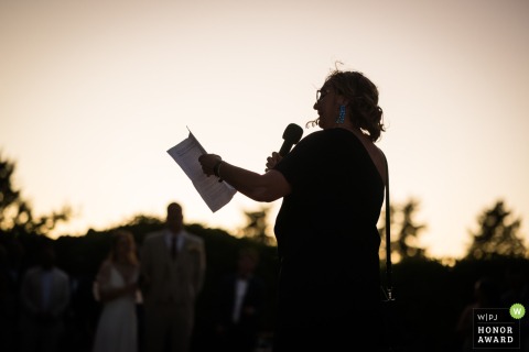The Groom’s Mother Delivers A Heartfelt Speech During A Golden Sunset In Brignoles Var France During a golden sunset in Brignoles, France, the groom’s mother delivers a heartfelt speech, her words resonating with warmth and emotion among the evening’s guests.