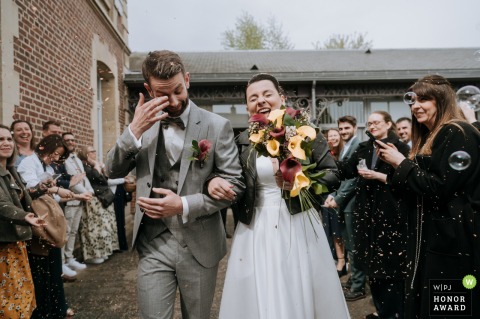 Laughter erupts as the couple exits their ceremony in Cires les Mello, France, radiating happiness and joy with every step among their friends and family.