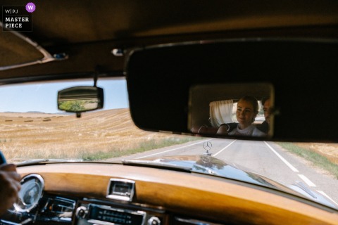 In Navarra, Spain, the bride and groom gaze out the window of their antique car, sharing a quiet moment together as they travel to the wedding venue after the ceremony.