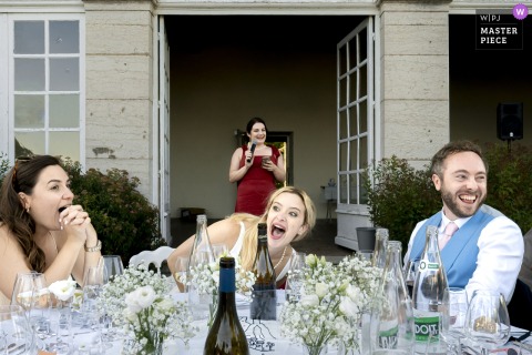 At Château de Montplaisant in Montagnat, Ain, a bridesmaid delivers a hilarious speech during the outdoor dinner, filling the celebration with laughter and joy.