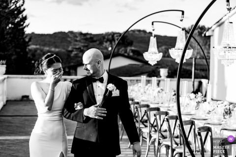 At Villa La Selva in Tuscany, the bride sees the wedding dinner table for the first time, covering her emotional face with her hand while holding the groom’s arm.