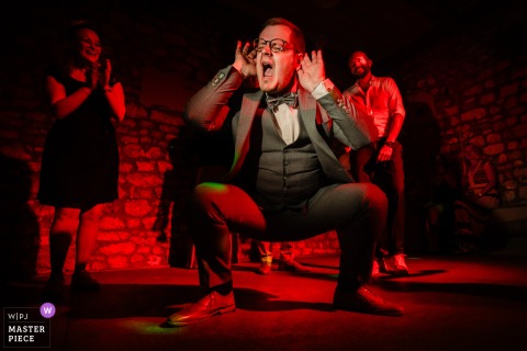 At Weingut Hahn in Alzey, a male guest dances energetically and squats under red party lights, bringing excitement and fun to the celebration.