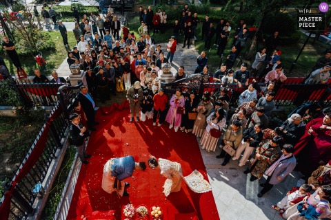At home in Binzhou, Shandong, a high-angle view shows a traditional Chinese bowing ceremony on a large red carpet during the wedding.