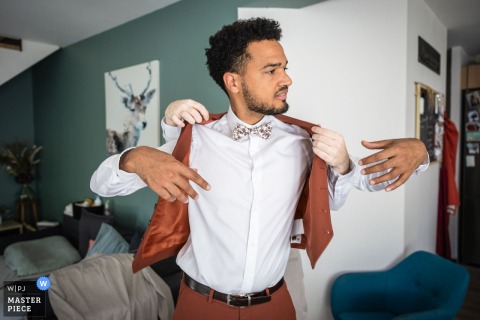 In Grenoble, Isère, France, the groom prepares for the big day with a little extra help, four hands adjusting his suit simultaneously.