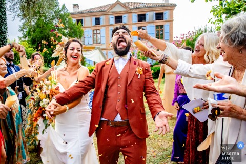 At Maison du Saula in Lafrançaise, the newlyweds are seen through an archway of guests forming a traditional haie d'honneur, capturing a joyful and celebratory wedding tradition as they make their entrance.