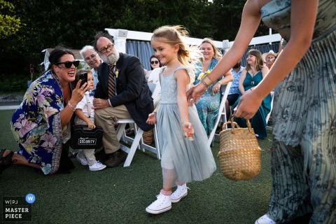 At Oceanview of Nahant in Nahant, MA, a flower girl joyfully tosses petals down the aisle while her mom and family cheer her on, capturing a sweet and supportive moment during the ceremony.