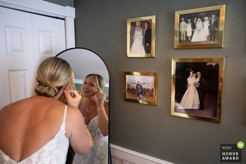 At her childhood home in Lowell, MA, a bride prepares for her wedding day while surrounded by nostalgic photographs from past family weddings.