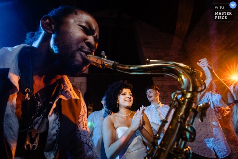 At Abbaye du Val des Choues, the lively sounds of a saxophonist fill the air as music plays at the party, bringing energetic, joyful vibes to the wedding celebration.