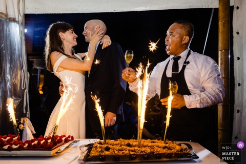 At Abbaye du Val Richer, a kiss shared by the couple at the cake is illuminated by a sparkling light, capturing a magical and romantic moment during the celebration.