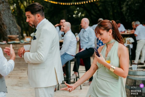 At Domaine du Petit Malherbes, a witness pins something to another witness’s jacket as part of a photo challenge, capturing playful camaraderie and lighthearted fun among the wedding party.