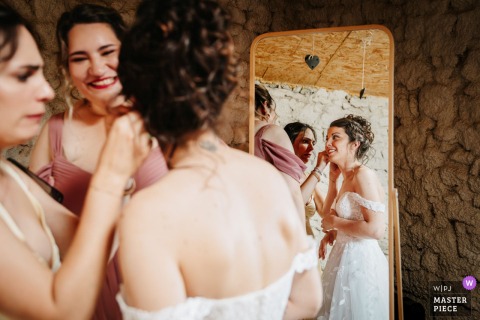 At Domaine des Monts du Lyonnais in Rhône, the bride carefully puts on her earrings, highlighting the delicate, detailed moments of wedding day preparation amidst anticipation and quiet concentration.