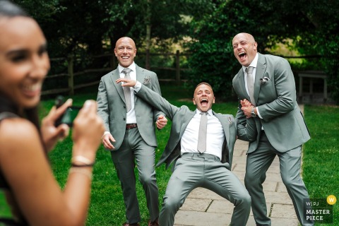 At Millbridge Court in Frensham, UK, a family photo moment is turned upside down when drinks are accidentally kicked over on the floor, prompting three men to burst into hysterical laughter.