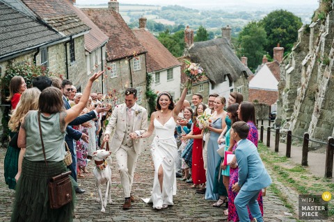 At Gold Hill in Shaftesbury, Dorset, the couple walks hand in hand through a confetti line outside the registry office at this iconic spot, capturing joyous celebration and the town’s picturesque charm.