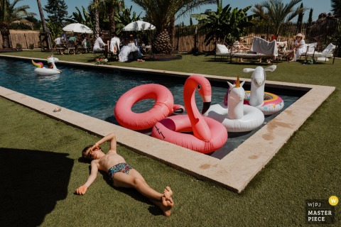 At Château du Parc Saint Lambert la Potherie, France, a child lounges by the pool during brunch, while the newlyweds and guests enjoy their meal in the background. The scene captures a relaxed, joyful moment after the festivities.