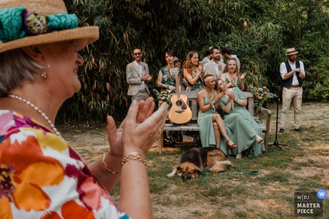 At Domaine des Loups in Niort, France, the bride's mother is in the foreground applauding joyfully during the secular ceremony, with the witnesses smiling in the background—a scene filled with pride and celebration.