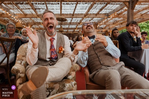 At Gîte de la Maronnière in Nantes, France, the newlyweds burst into laughter during a speech at the reception dinner, capturing a joyful and candid moment of celebration surrounded by family and friends.