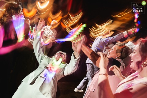 A lively, illuminated limbo dance sequence energizes the party in Noord Holland, as guests challenge each other under glowing motion blurred  lights.