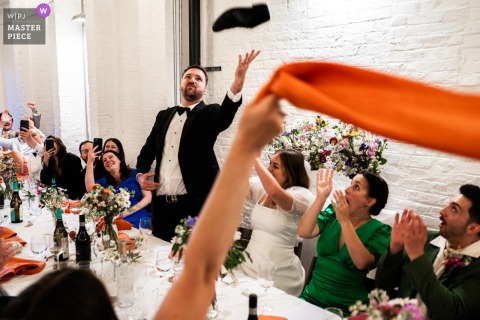 Shoe Flies Over Groom’s Head At 100 Barrington Brixton Party At 100 Barrington in Brixton, a lively party scene unfolds as a shoe flies over the groom’s head while guests partake in the playful tradition of drinking from the shoe, capturing the wild spirit of the celebration.
