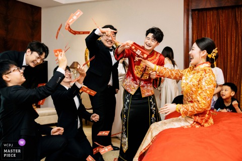 Inside the bridal suite at the Shangri-La Hotel, Pudong, Shanghai, the bride and groomsmen share laughs as they play traditional wedding door games, capturing lively energy and joyful traditions before the ceremony.