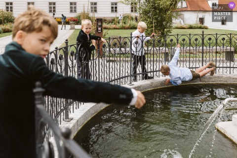 At Church Stift Wilhering in Austria, a playful scene unfolds as young boys embark on a ring rescue mission in the koi pond during the wedding.