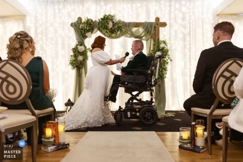 At The Shandon Hotel in Dunfanaghy, Co Donegal, the bride tenderly holds the microphone for her groom, allowing him to read his vows aloud. The moment highlights their partnership and quiet connection during the ceremony.