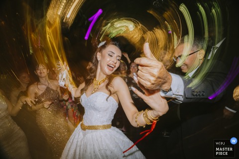 At Istanbul Raffles Hotel, a long exposure captures the bride dancing with her father on stage. Circular lights from motion blur swirl around them, creating a dynamic and celebratory scene full of movement and emotion.