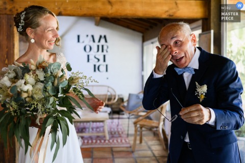 At Ferme d'En Chon, the bride’s father removes his glasses to wipe away tears after seeing his daughter in her wedding dress, while she smiles at him. The moment radiates deep emotion and heartfelt connection.