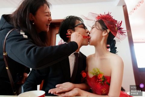 At home in Taiyuan, Shanxi, the couple shares a traditional moment as the mother feeds them wedding dumplings with her chopsticks. The intimate scene highlights family bonds and cultural rituals on their special day.