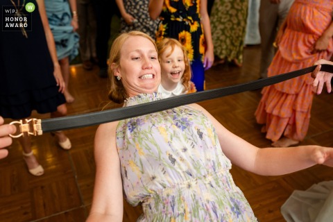 On the dance floor at a private residence in Newport, VT, a wedding guest and her daughter gleefully attempt the limbo, using a belt as their playful challenge.