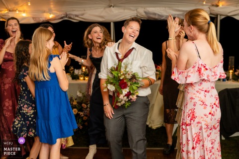 A spontaneous moment at a private residence in Hartland, VT, as a wedding guest reacts with excitement and surprise after catching the bouquet toss.