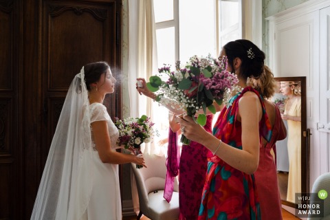 Moments before the big reveal at Château de la Frette en Isère, the bride adds a final touch of perfume, heightening the anticipation for her soon-to-be spouse.