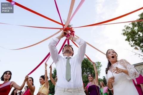 A touching moment at Le Mas Girodier in Ardèche, as emotions run high during the ribbon game for the bride’s bouquet—captured as guests participate in this joyful, heartfelt wedding tradition.