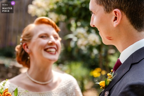 A playful moment captured in Omaha, Nebraska, as the couple shares their first look. She kisses him on the cheek, leaving a red lipstick mark, and beams with happiness—perfectly documented and full of personality.
