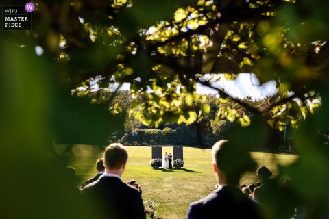 A touching moment captured at Mountain Top Inn in Chittenden, VT, as the bride and her mother walk down the aisle during the ceremony, beautifully documented from behind through a foliage arch.
